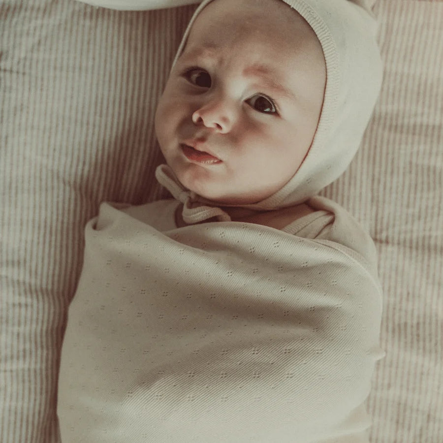 Baby wrapped in the Lovely Littles Oatmilk Pointelle Blanket
